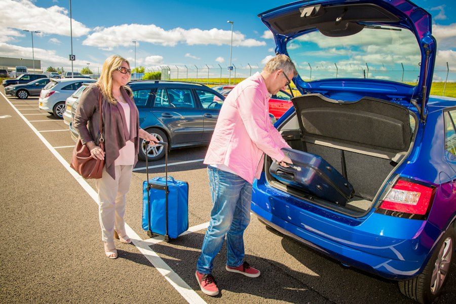 A couple loading their luggage into a waiting car