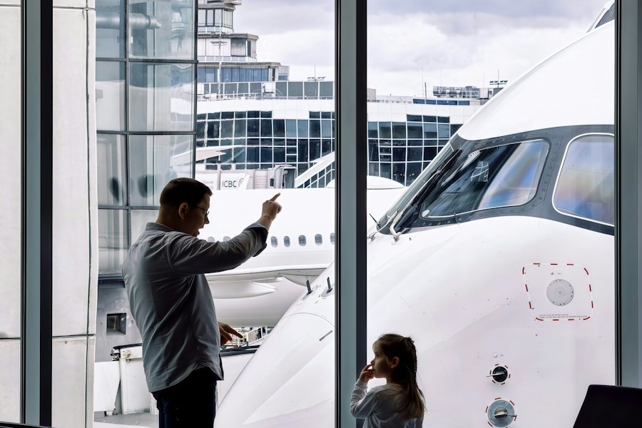 A father and daughter watching an aircraft from the terminal window