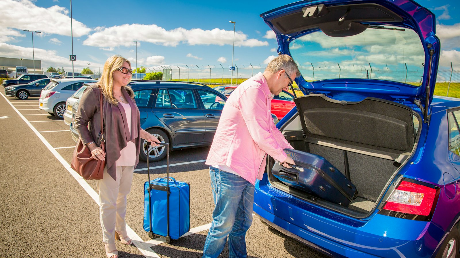 A couple loading luggage into a waiting car